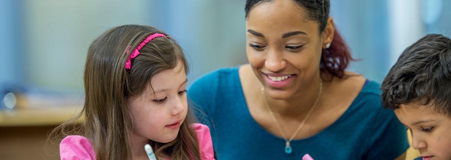 Banner for paraprofessional webpage; Image of a female paraprofessional working with children in a school setting