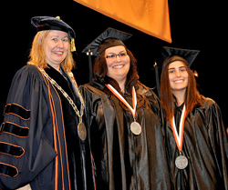 Acting President Meg Benke congratulates Jennifer Jorgensen and her sister Katelyn, one of the student speakers.