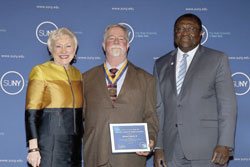 SUNY Chancellor Nancy L. Zimpher stands next to Edward Shevlin III '11, '14 who is holding his Chancellor's Award for Student Excellence. Zimpher and Shevlin were joined by the college's provost and vice president for academic affairs, Alfred Ntoko, at the 2015 award ceremony for all recipients held in Albany, N.Y./Photo Joe Putrock for SUNY